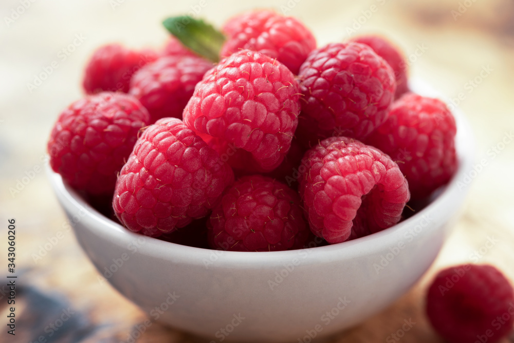 fresh organic raspberries in a white bowl with a bit of mint fresh organic raspberries in a white bowl with a bit of mint