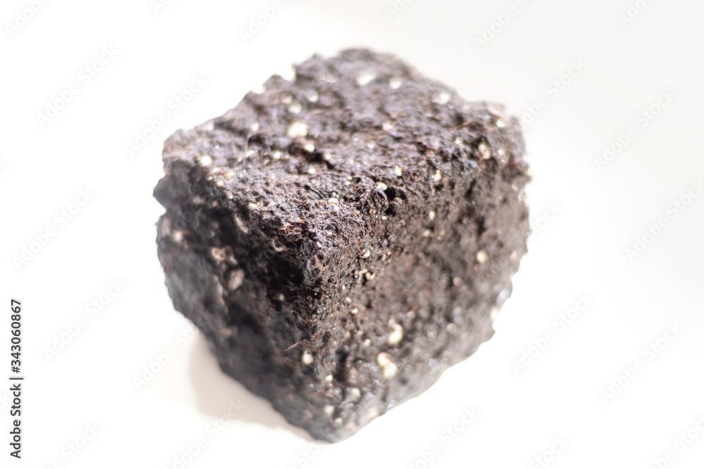 A separate object in the form of a cube from the ground on a light background in soft focus A separate object in the form of a cube from the ground on a light background in soft focus