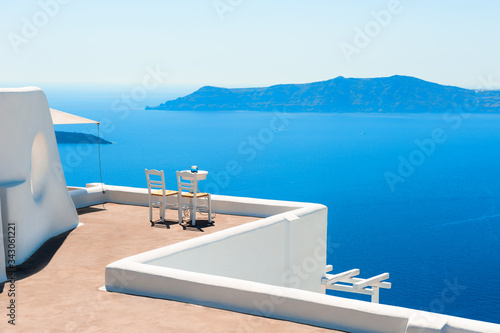 Two chairs on the terrace with sea view. White architecture on Santorini island, Greece. Travel destinations concept