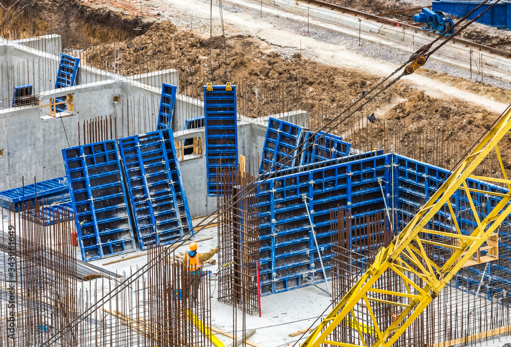 Construction workers install formwork and iron rebars or reinforcing bar for reinforced concrete partitions at the construction site of a large residential building.