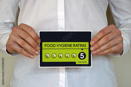 Restaurant manager holds a sticker with Food Hygiene rating 5 from The United Kingdom Food Standards Agency