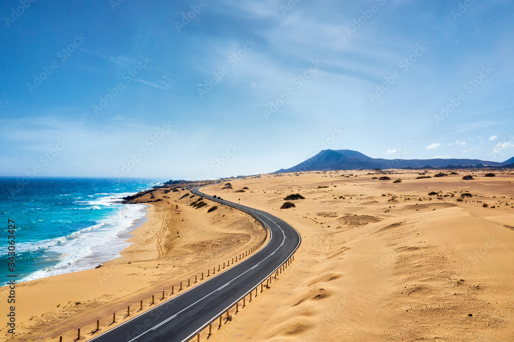 Rocky coastline and highway with golden sand and blue water