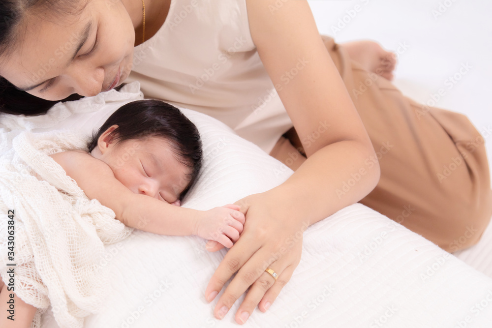 Selective focus beautiful Asian mother with wedding ring nurturing adorable infant with love and care, mom hold tiny finger newborn baby while sleeping comfortable on bed at home. motherhood lifestyle Selective focus beautiful Asian mother with wedding ring nurturing adorable infant with love and care, mom hold tiny finger newborn baby while sleeping comfortable on bed at home. motherhood lifestyle