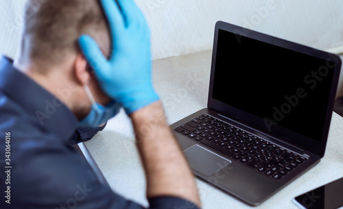 Entrepreneur At Laptop Cupping Head In Hands In Despair Indoors