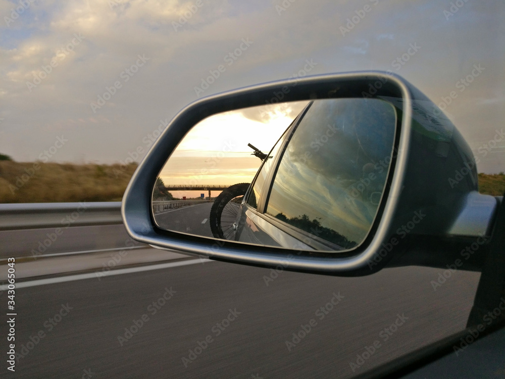 View in rear mirror on roadtrip with bikes on back of car