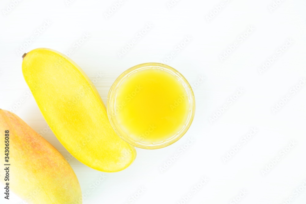 Mango juice in a glass and yellow fresh mango on the table close up