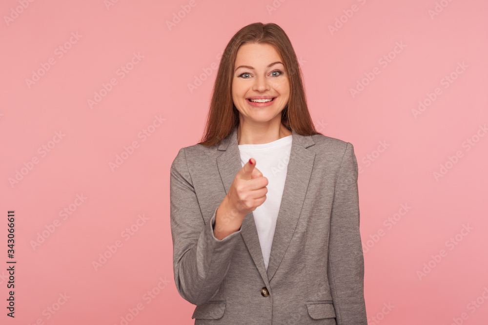 Hey you! Portrait of happy optimistic young woman in business suit making choice with indicating finger, looking delighted positive, showing lucky winner. studio shot isolated on pink background Hey you! Portrait of happy optimistic young woman in business suit making choice with indicating finger, looking delighted positive, showing lucky winner. studio shot isolated on pink background