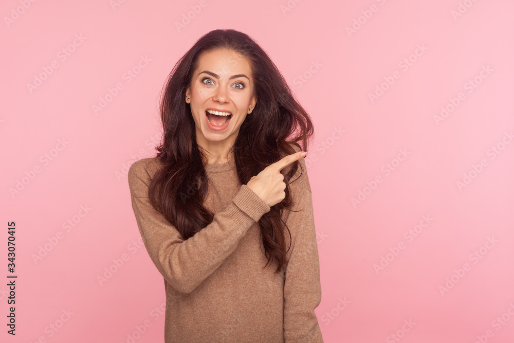 Wow, attention to advertising! Portrait of surprised shocked young woman with brunette hair pointing aside, showing copy space for commercial text, blank wall with idea presentation. studio shot Wow, attention to advertising! Portrait of surprised shocked young woman with brunette hair pointing aside, showing copy space for commercial text, blank wall with idea presentation. studio shot