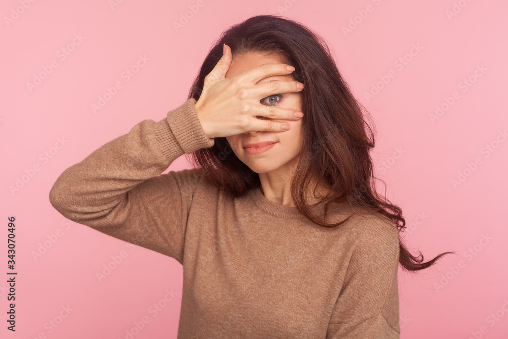 Portrait of nosy prying inquisitive young woman with brunette hair peeking through fingers with curious expression, shy and afraid to watch secret. indoor studio shot isolated on pink background Portrait of nosy prying inquisitive young woman with brunette hair peeking through fingers with curious expression, shy and afraid to watch secret. indoor studio shot isolated on pink background