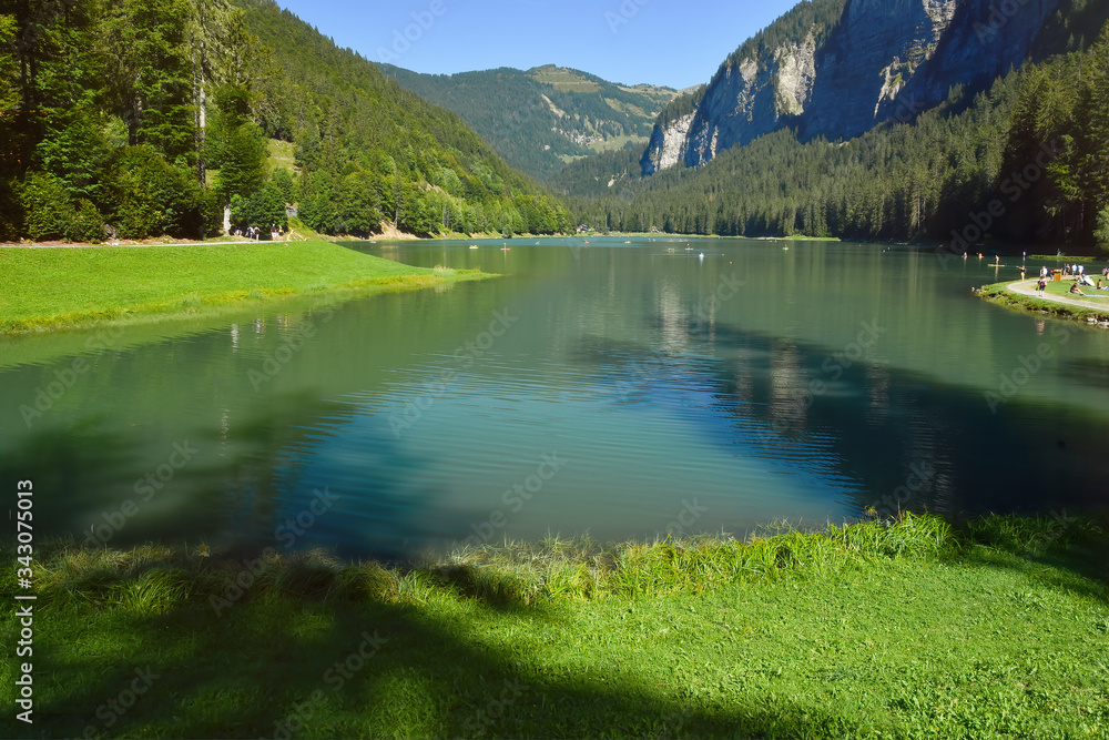 Fototapeta premium Lake of Montriond, natural lake in Portes du Soleil, Haute -Savoie region, France, an attraction for many tourists, with swimming area, fishing, canoeing.