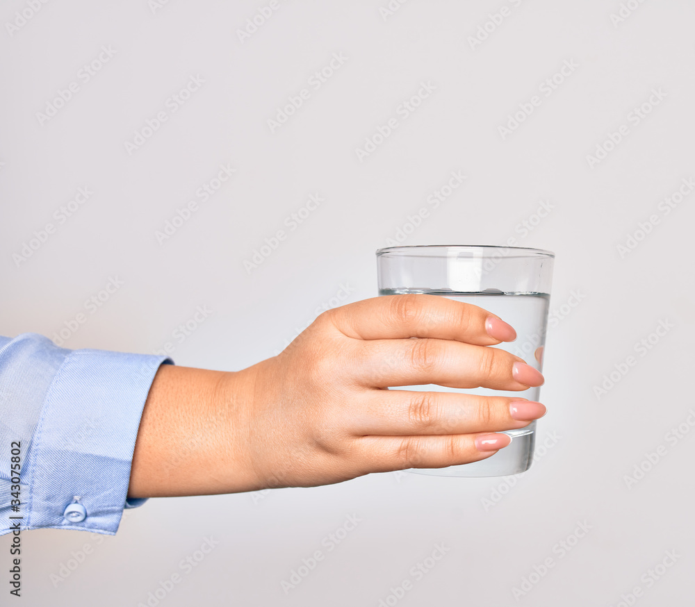 Hand of caucasian young woman holding glass of water over isolated white background Hand of caucasian young woman holding glass of water over isolated white background