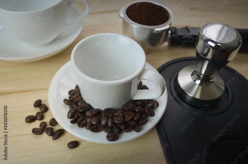 White cup with coffee beans placed in the coaster. White cup with coffee beans placed in the coaster.