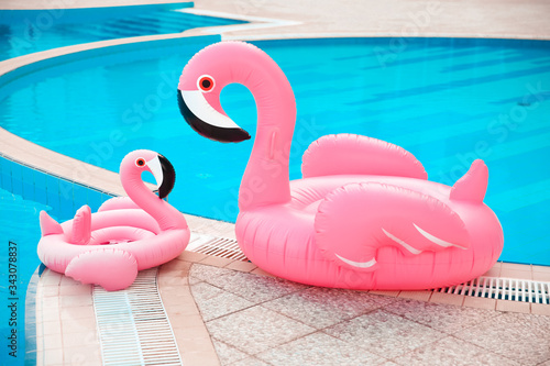 Family look. Two Pink pool floats flamingo by blue water, pool party toy. Giant Inflatable Swimming Ring. Summer vacation holiday luxurious resort.