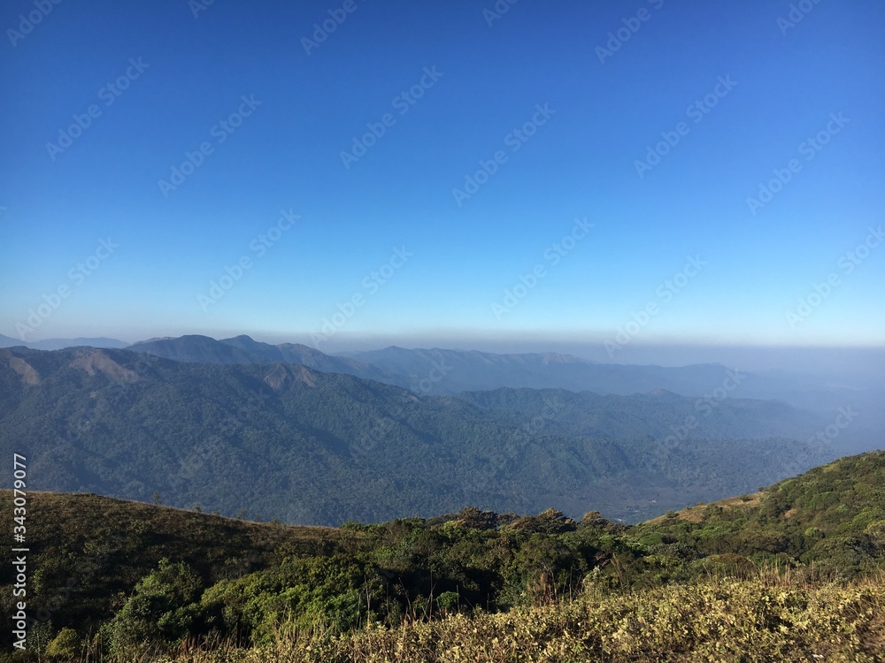 The scenic view from Nishani Betta Peak, Coorg, India. Blue sky, great mountains and valleys.