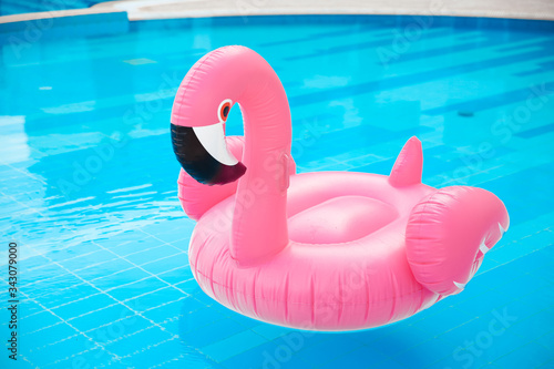 Pink pool float flamingo by blue water, pool party toy. Giant Inflatable Swimming Ring. Summer vacation holiday luxurious resort.