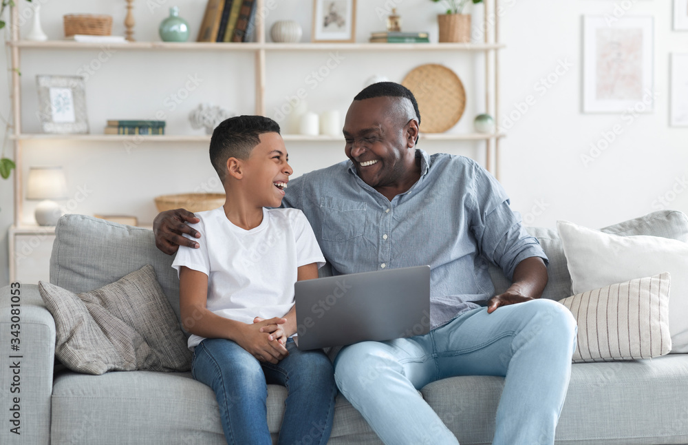 African Grandfather And Grandson Using Laptop Together, Watching Movie At Home African Grandfather And Grandson Using Laptop Together, Watching Movie At Home