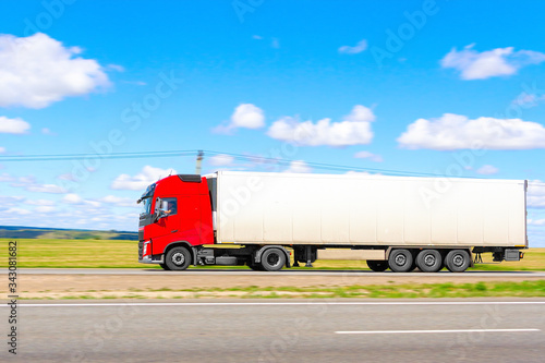 traveling truck with a red cab on a summer day on a blurred background