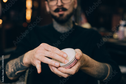 balm-wax. beard oils. barber shop beard care.jar with wax in the hands of a barbershop
