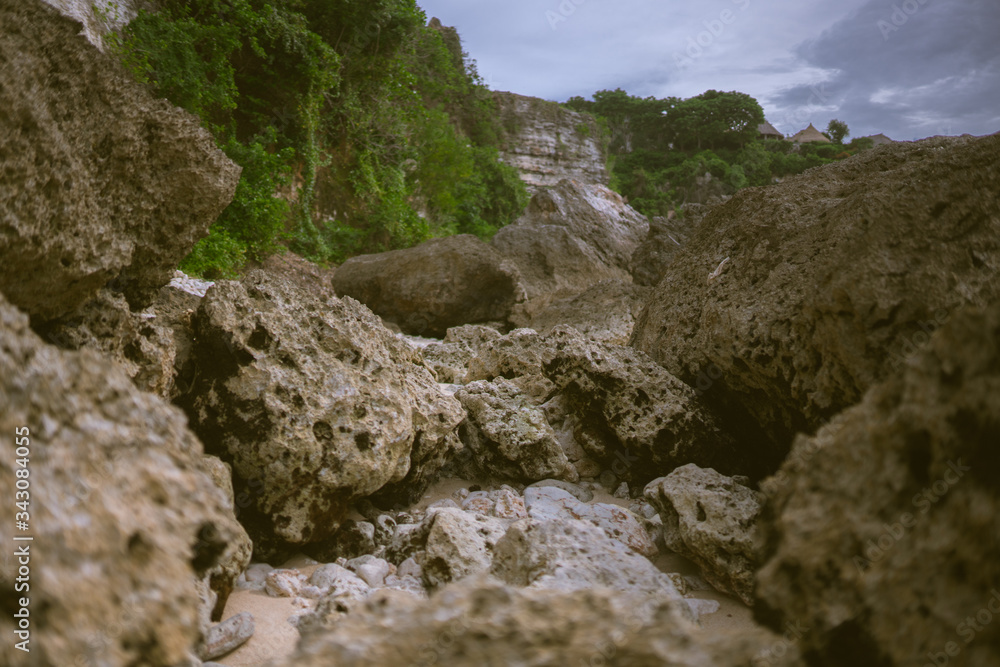 Beautiful deserted beach on the island of Bali at sunset. Rocks and nature. Plants and houses on the coast. Tropical paradise. Stones and white sand on the ocean Beautiful deserted beach on the island of Bali at sunset. Rocks and nature. Plants and houses on the coast. Tropical paradise. Stones and white sand on the ocean