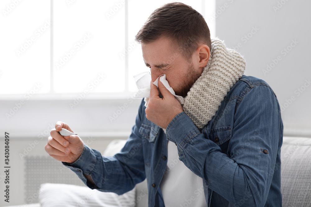 Sick man with fever blowing his runny nose at home Sick man with fever blowing his runny nose at home