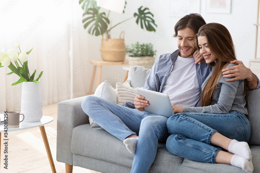 Positive couple shopping online at home, using digital tablet Positive couple shopping online at home, using digital tablet