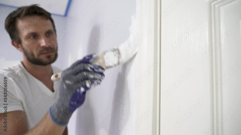 Close up of painter hands with gloves painting the wall edge by door frame. Close up of painter hands with gloves painting the wall edge by door frame.