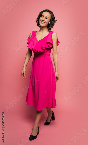 Heading to the party. Full-length photo of a stunning young woman in a long magenta dress, who is walking ahread with a bright smile.