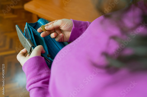 Señora blanca de edad media saca una moneda de su cartera vacía debido a que no tiene dinero por la crisis económica. Se ven las dos manos y la moneda es dorada. Son 10 céntimos. photo