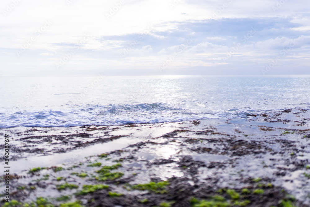 Beautiful deserted beach on the island of Bali at sunset. Rocks and nature. Plants and houses on the coast. Tropical paradise. Stones and white sand on the ocean Beautiful deserted beach on the island of Bali at sunset. Rocks and nature. Plants and houses on the coast. Tropical paradise. Stones and white sand on the ocean