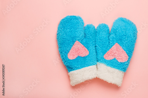 Pair of mittens with pink heart symbol on pink background