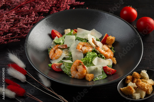 caesar salad with shrimp on a dark wooden background photo