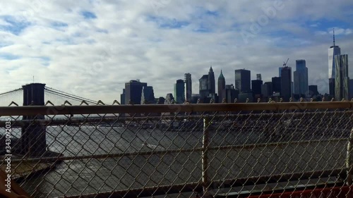Glimpse of Manhattan and the Brooklyn Bridge interspersed with the passage of metal beams from the subway window as it crosses the East River on a bridge in the direction of Brooklyn District