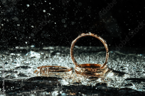 A close up of gold wedding rings under the spray of water