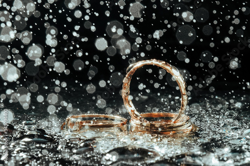 A close up of gold wedding rings under the spray of water