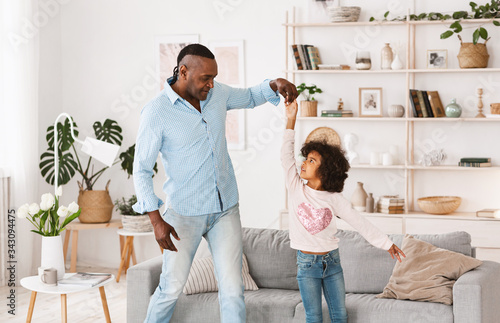 Stay home family fun. Cheerful older man with his granddaughter dancing in living room