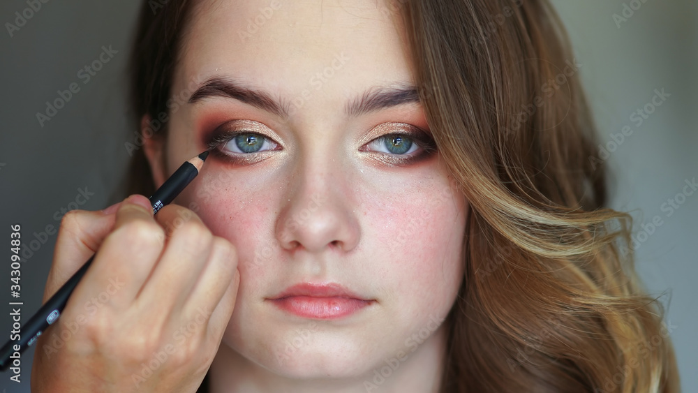 Girl makeup artist paints the eyes of a young girl Girl makeup artist paints the eyes of a young girl