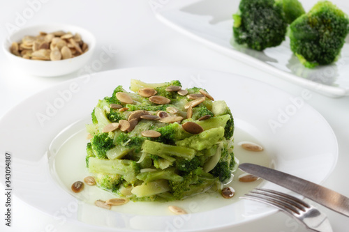 Boiled broccoli with pumpkin seeds on a white plate on the table