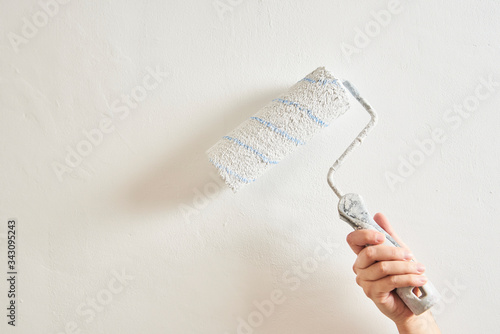 Woman painting a wall in white