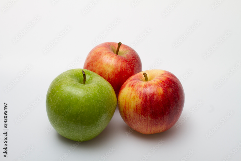 Three apples, one green and two red-yellow on a light background Three apples, one green and two red-yellow on a light background