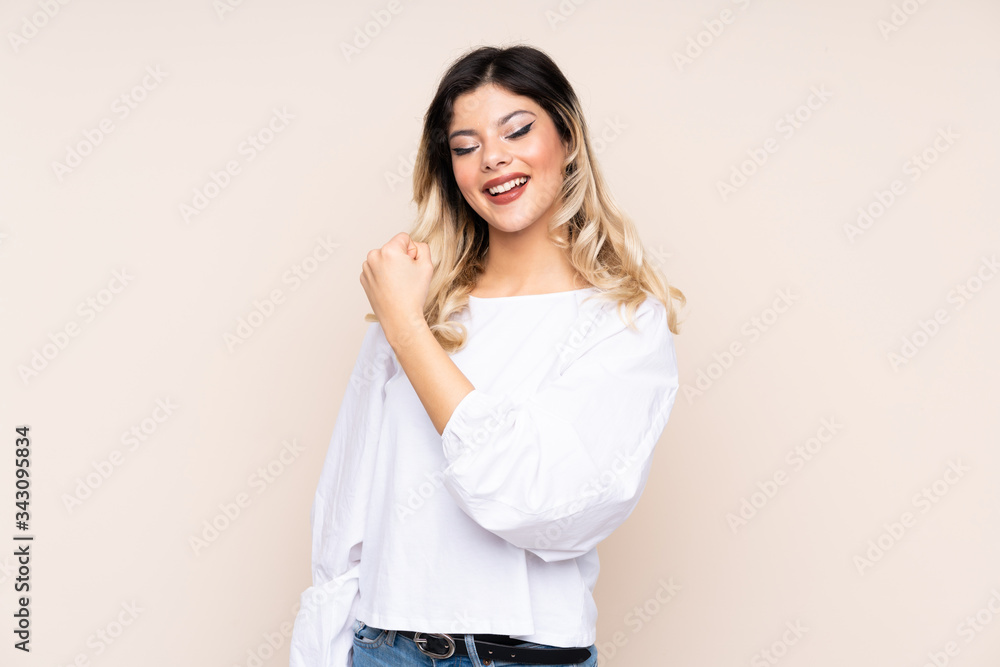 Teenager girl isolated on beige background celebrating a victory Teenager girl isolated on beige background celebrating a victory