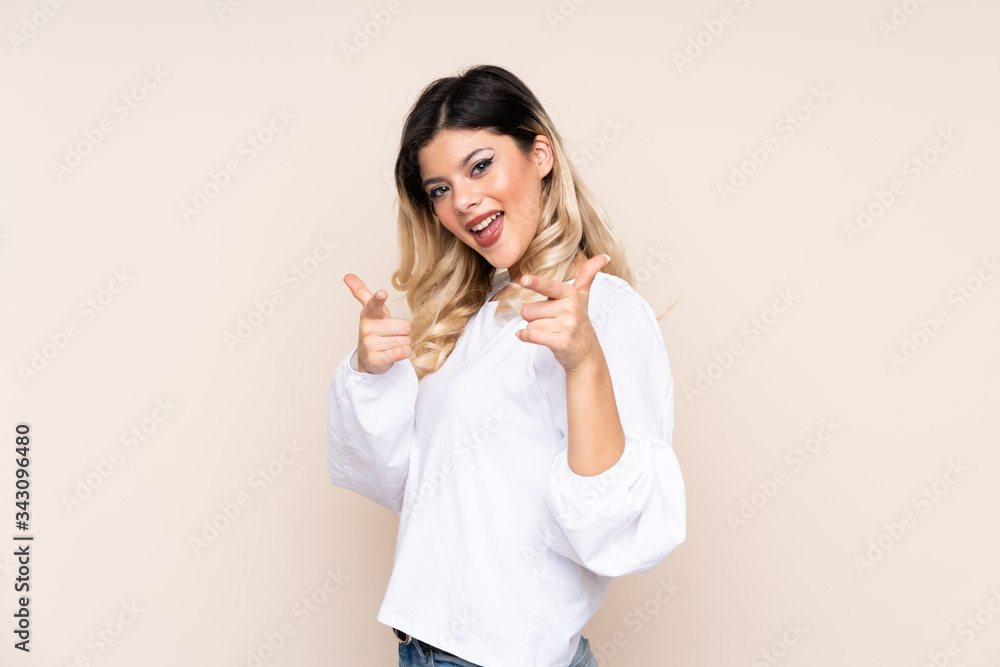 Teenager girl isolated on beige background pointing to the front and smiling Teenager girl isolated on beige background pointing to the front and smiling