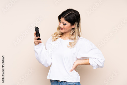 Teenager girl isolated on beige background making a selfie