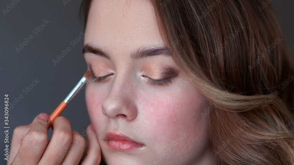 Girl makeup artist paints the eyelids of a girl model