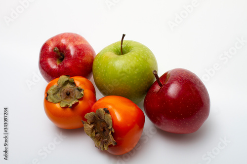 Three apples and two persimmons on a light background