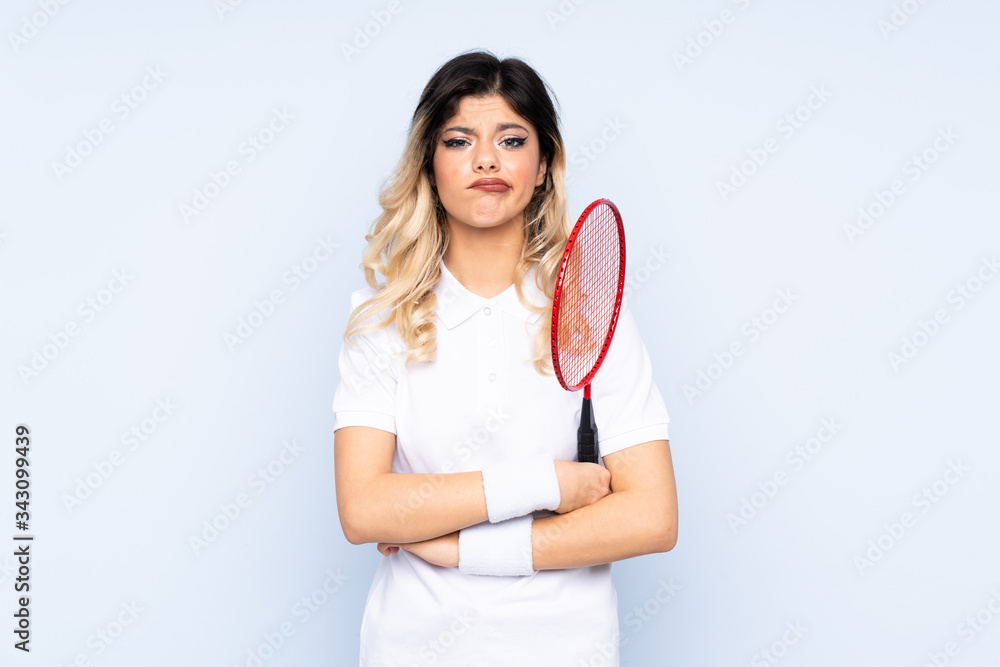 Teenager girl playing badminton isolated on blue background sad Teenager girl playing badminton isolated on blue background sad