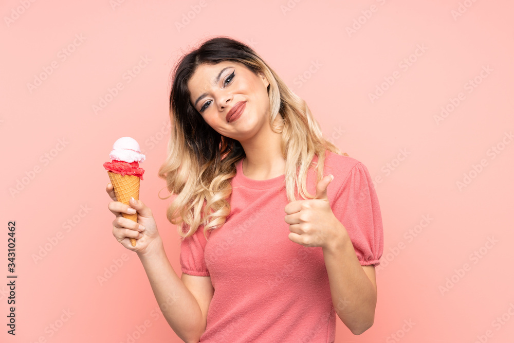 Teenager girl holding a cornet ice cream isolated on pink background with thumbs up because something good has happened Teenager girl holding a cornet ice cream isolated on pink background with thumbs up because something good has happened