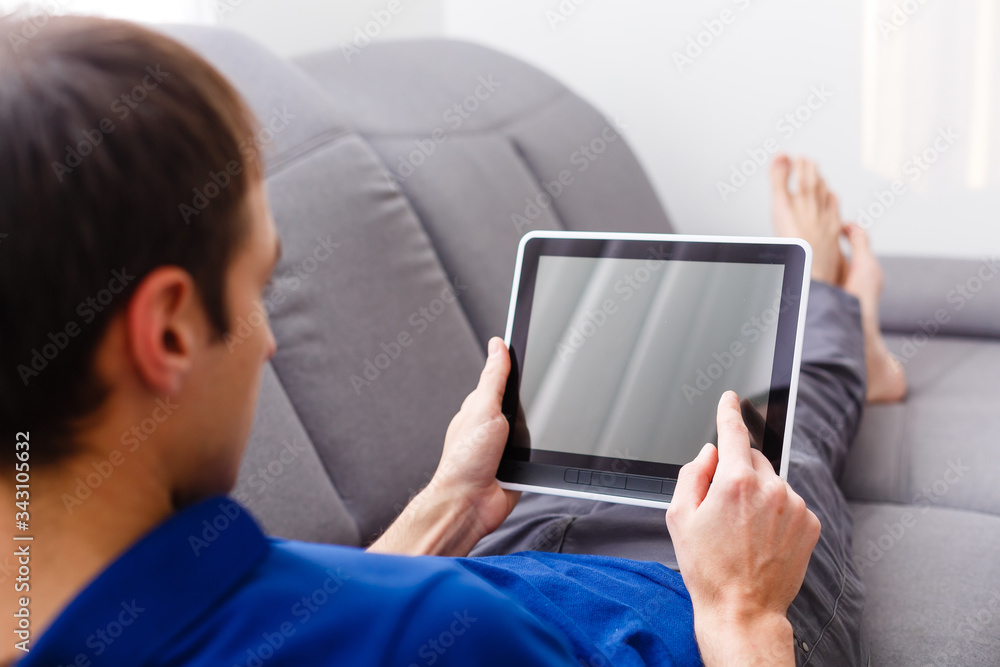 Man sitting in sofa using electronic tablet