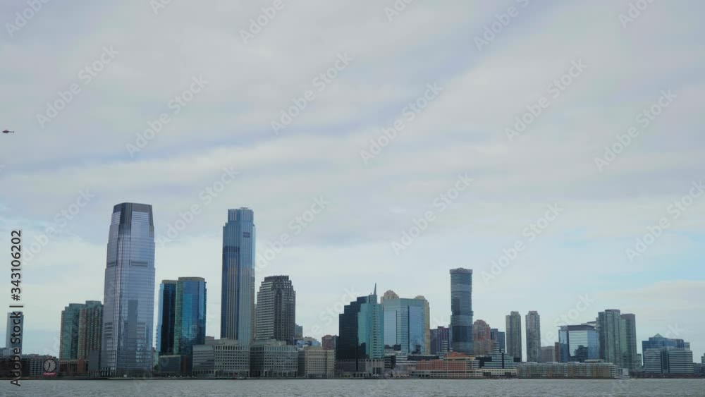 A helicopter flies over Jersey City's skyscrapers from right to left on a cloudy and rainy day A helicopter flies over Jersey City's skyscrapers from right to left on a cloudy and rainy day