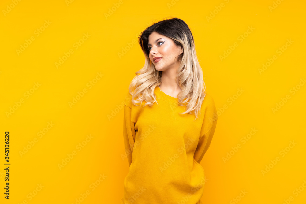 Teenager girl isolated on yellow background and looking up Teenager girl isolated on yellow background and looking up