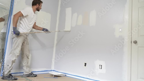 Painter man painting the wall in home, with paint roller and white color paint. Room renovations at house.